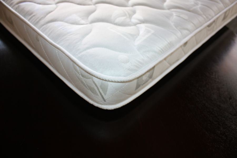 Close-up of the mattress corner showing the quilted top and piped edge